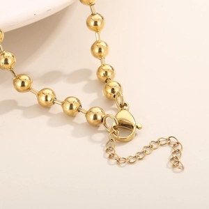 Golden bead necklace featuring a secure lobster clasp and adjustable extension chain