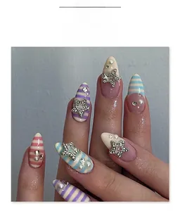 Detalle de uñas almendradas con rayas de colores, estrellas plateadas, perlas y strass