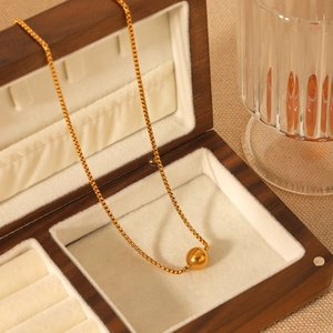 Close-up of 18K gold stainless steel box chain and bead pendant in a wooden jewelry box
