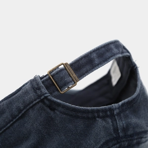 Close-up of the vintage bronze metal buckle and washed denim texture on a flat top cap