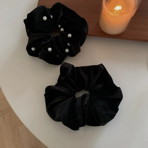 Elegant large black velvet scrunchies with white pearl accent on a warm wooden table