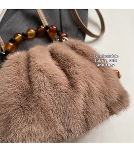 Detail of plush brown bucket bag featuring amber bead handle and soft faux fur texture