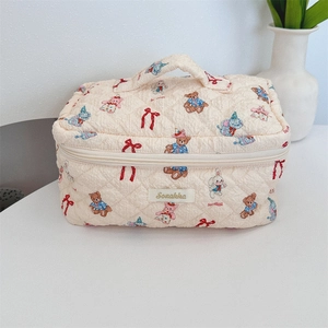 Top view of beige quilted makeup bag with teddy bear pattern and top handle detail