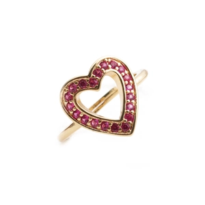 Macro detail of gold-plated heart ring featuring pavé-set red cubic zirconia crystals