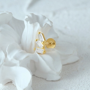 Close-up of golden tassel earring with baguette diamonds on white plaster flower