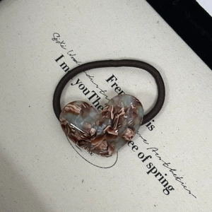 Close-up of heart-shaped marble acetate pendant on a black elastic hair tie