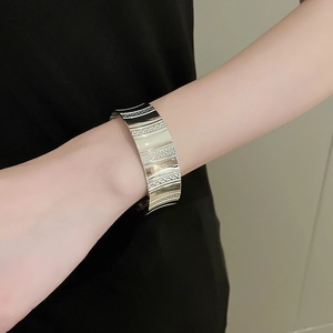 Close-up of minimalist silver wide open cuff bracelet with textured striped pattern