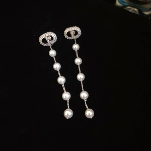 Macro shot of silver tassel earrings with zircon CD logo and white hanging pearls