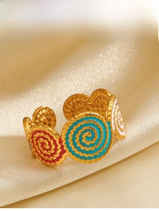 Macro detail of gold spiral ring with pink, blue, and white enamel inlay on silk