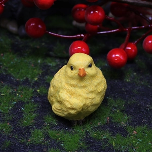 Miniature resin yellow chick ornament with feather texture in a mossy garden setting