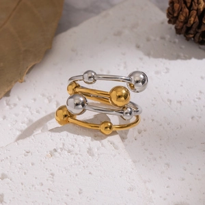 Elegant gold and silver ball stackable rings on a textured stone surface with natural light