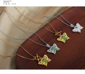 Détail de colliers papillon à fermoir OT avec émail vert et finition dorée