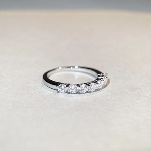 Classic 925 sterling silver band with 7 round Moissanite stones in a row on grey surface
