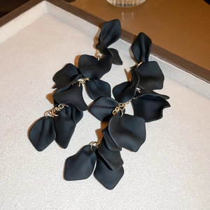 Macro shot of matte black layered flower petals and gold metal link tassel earrings
