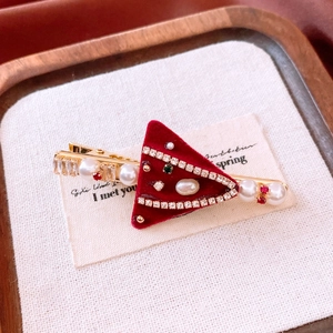 Detail of red velvet triangle hair clip with pearls and rhinestones on a gold base