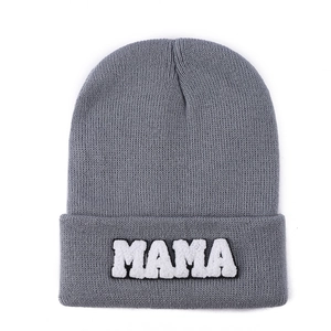Close-up of grey knitted beanie featuring white MAMA towel embroidery on folded brim