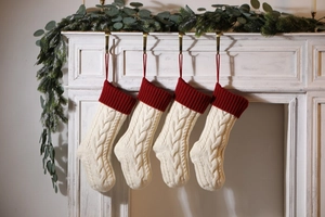 Close-up of four cable knit Christmas stockings hanging on a white fireplace mantel