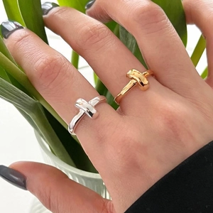 Detailed close-up of polished silver and gold knot rings featuring a modern minimalist style