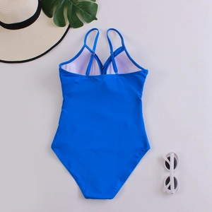 Back view of a vibrant royal blue one-piece swimsuit with cross straps on a summer background