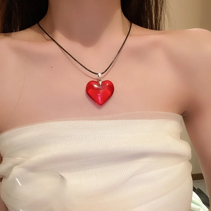 Gros plan d'un collier avec pendentif cœur en verre rouge sur un cordon noir minimaliste