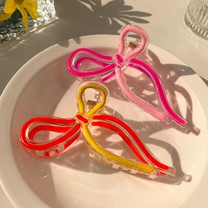 Detailed close-up of bow-shaped jelly hair claws in pink and red-yellow colors