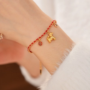 Detail of red braided lucky bracelet with gold dragon pendant and sparkling zircon
