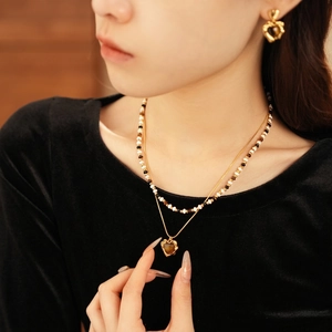 Gold-plated layered necklace with heart-shaped tiger eye pendant on a female model