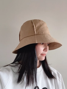 Detail of khaki nylon sun hat with reinforced stitched brim worn by female model