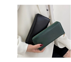 Detailansicht langer Lederbrieftaschen in Schwarz und Dunkelgrün mit Goldreißverschluss