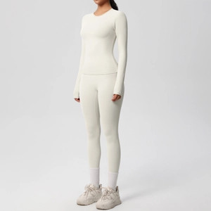 Dettaglio del tessuto a maglia elastica del set da yoga bianco crema con maglia e pantaloni
