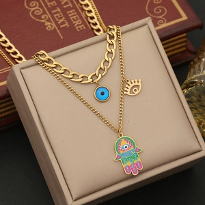 Detail of double-layer gold necklace featuring enamel Hamsa hand and blue evil eye charms