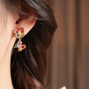 Close-up of model wearing vintage golden butterfly earrings with colorful zircons
