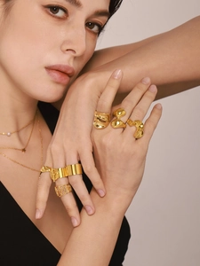 Close-up of layered 18K gold plated rings and necklaces with pearl and star charms