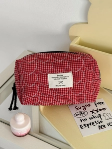Détail de la pochette matelassée à carreaux rouges avec cœurs blancs et étiquette
