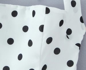 Gros plan du tissu blanc à pois noirs avec une texture lisse et délicate