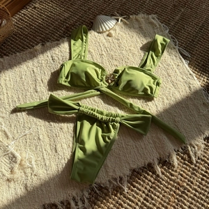 Detailed close-up of olive green bikini set with gold starfish accessory on flat lay mat