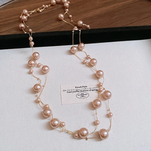 Detail of double-layer necklace featuring champagne pearls and fine gold-plated chains