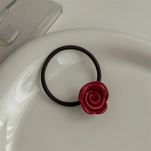 Close-up of a red resin rose charm on a black high-elastic hair tie on white plate