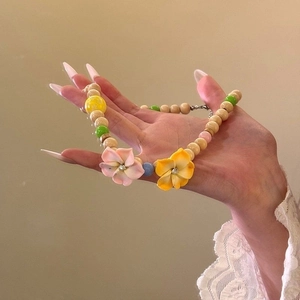 Detail of multi-layer necklace with wooden beads and colorful resin flower pendants
