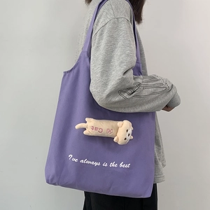 Detail of purple canvas tote bag featuring a 3D plush cat doll and letter embroidery