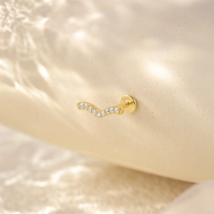 Detailed close-up of S925 hallmark on a wavy gold-plated earring with zircons