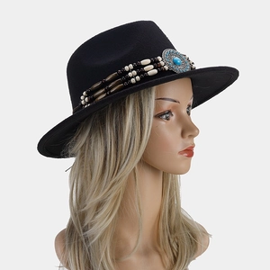 Détail d'un chapeau fedora noir avec chaîne ethnique perlée et badge en turquoise