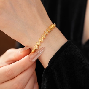 Detail of fan-shaped bangle with gold plating and zircons on a model wrist