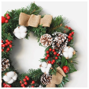 Close-up of Christmas wreath featuring red berries, snowy pine cones and white cotton balls