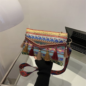 Detail of bohemian woven envelope bag with colorful fringe and ethnic patterned strap