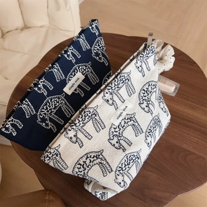 Close-up of canvas makeup bags with giraffe prints and metallic zippers on wooden table