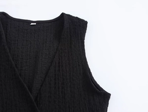 Detail shot showing the V-neckline and textured pleated fabric of the black sleeveless top
