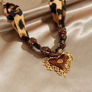Collier ruban léopard avec pendentif cœur sur fond de soie dorée élégant