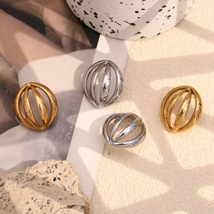Detail view of hollow curved spherical earrings in gold and silver finish on a textured surface