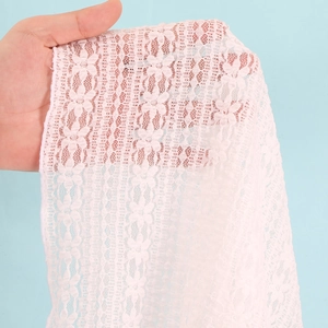 Detailed close-up of pink lace fabric with intricate 3D floral texture and sheer mesh